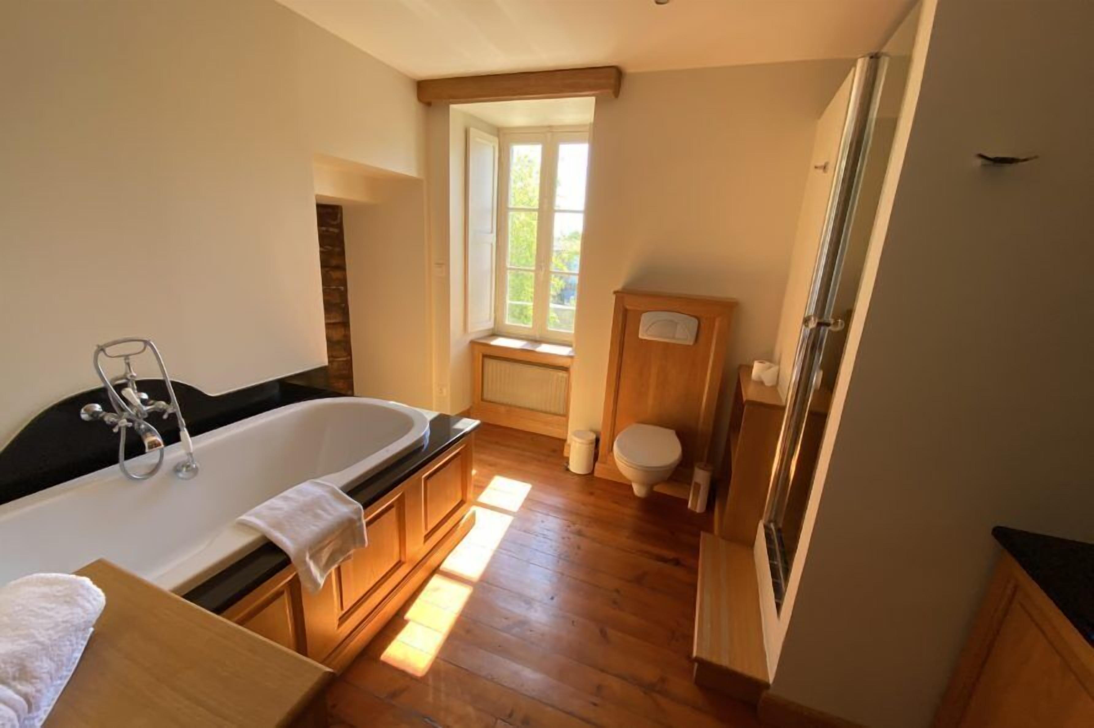 Een badkamer met een bad, toilet en raam.