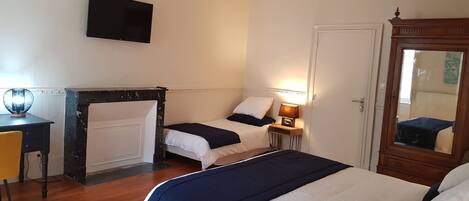 A hotel room with a bed, bedside table, lamp, TV, and a mirror.