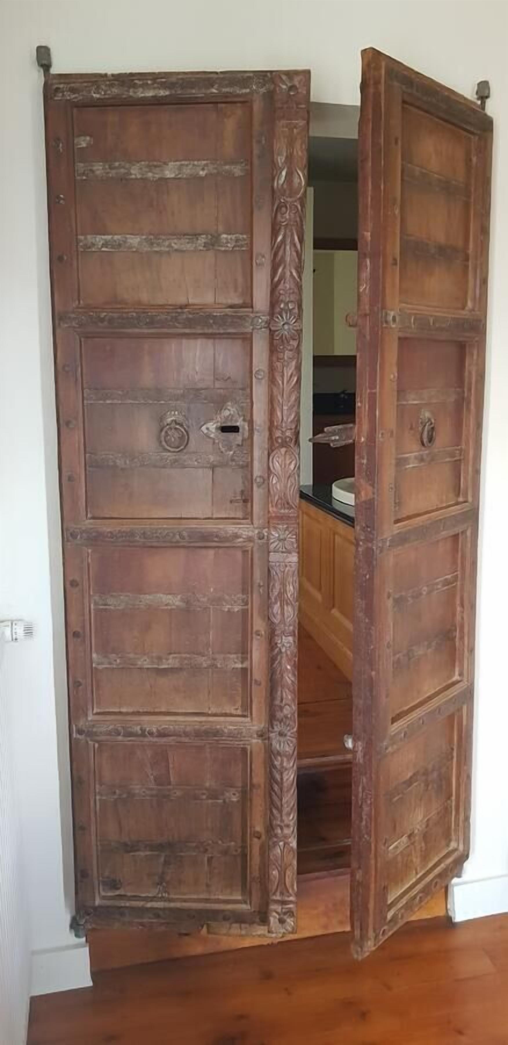 Una puerta de madera grande con tallas intrincadas y un tirador metálico.