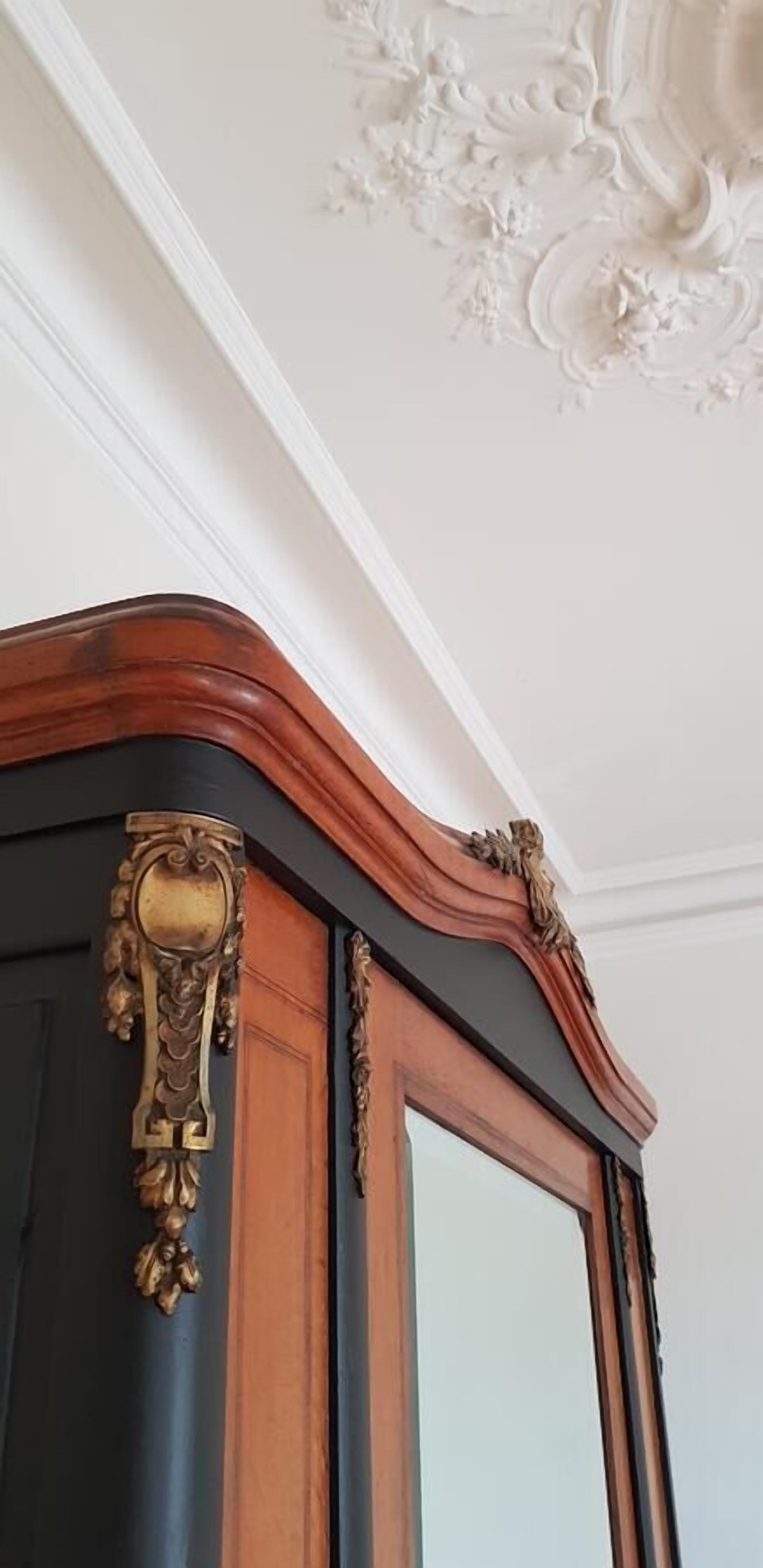 A corner of a room with a dark wooden cabinet and a white ceiling with a decorative molding.