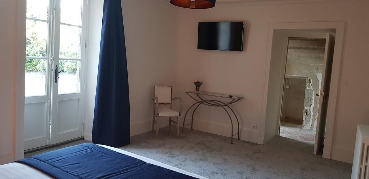 Une chambre à coucher avec un lit, une chaise, une télévision et un bureau.