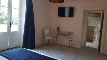 Une chambre à coucher avec un lit, une chaise, une télévision et un bureau.
