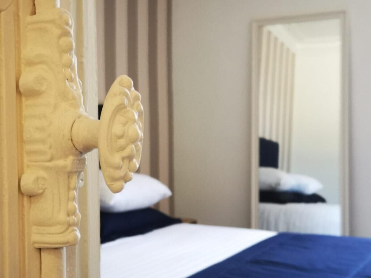 Ein Schlafzimmer mit einem Bett, einem Holz-Kopfteil und einem Spiegel, der den Raum widerspiegelt.