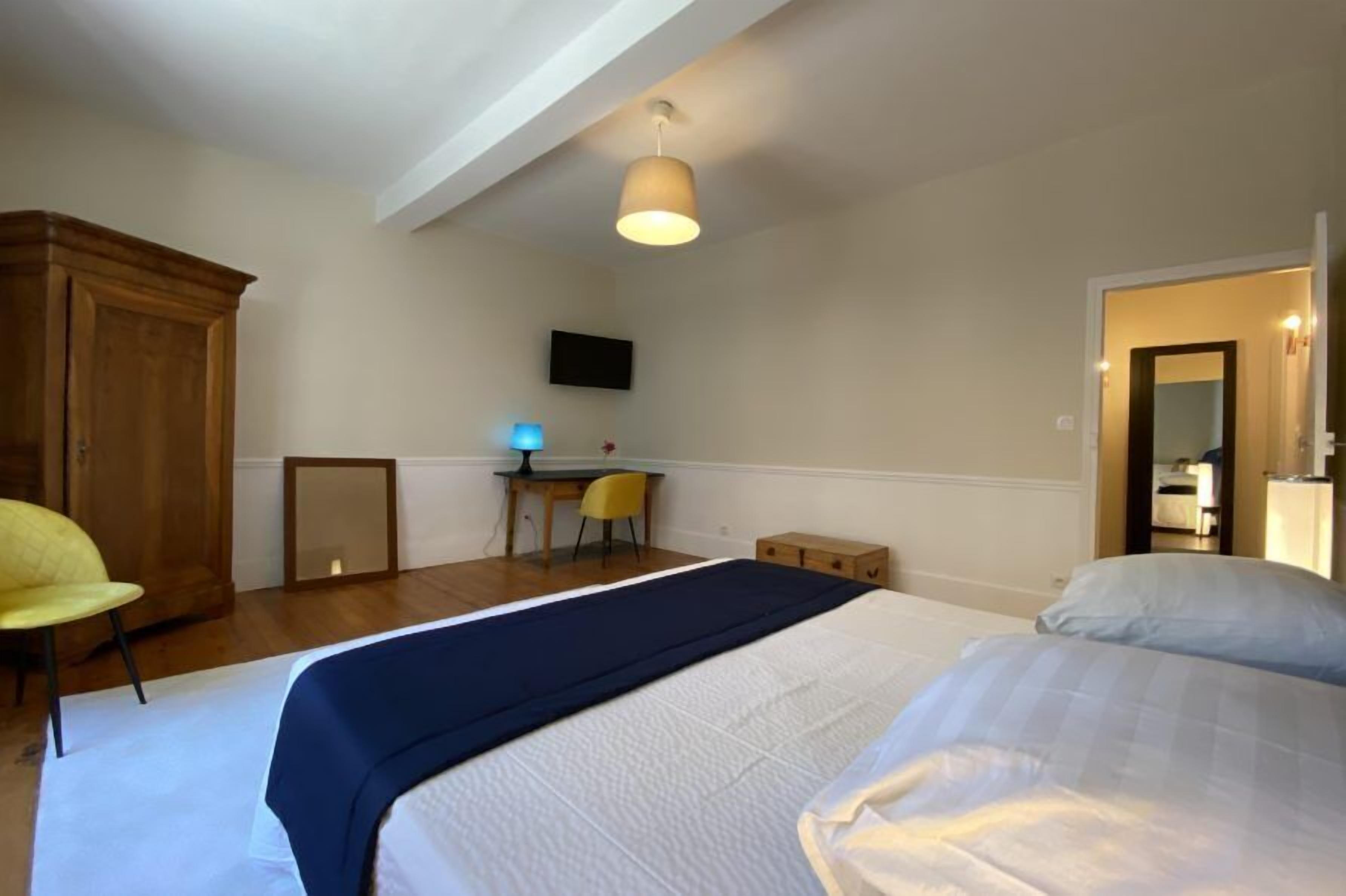 A bedroom with a bed, a desk, a chair, and a wardrobe.