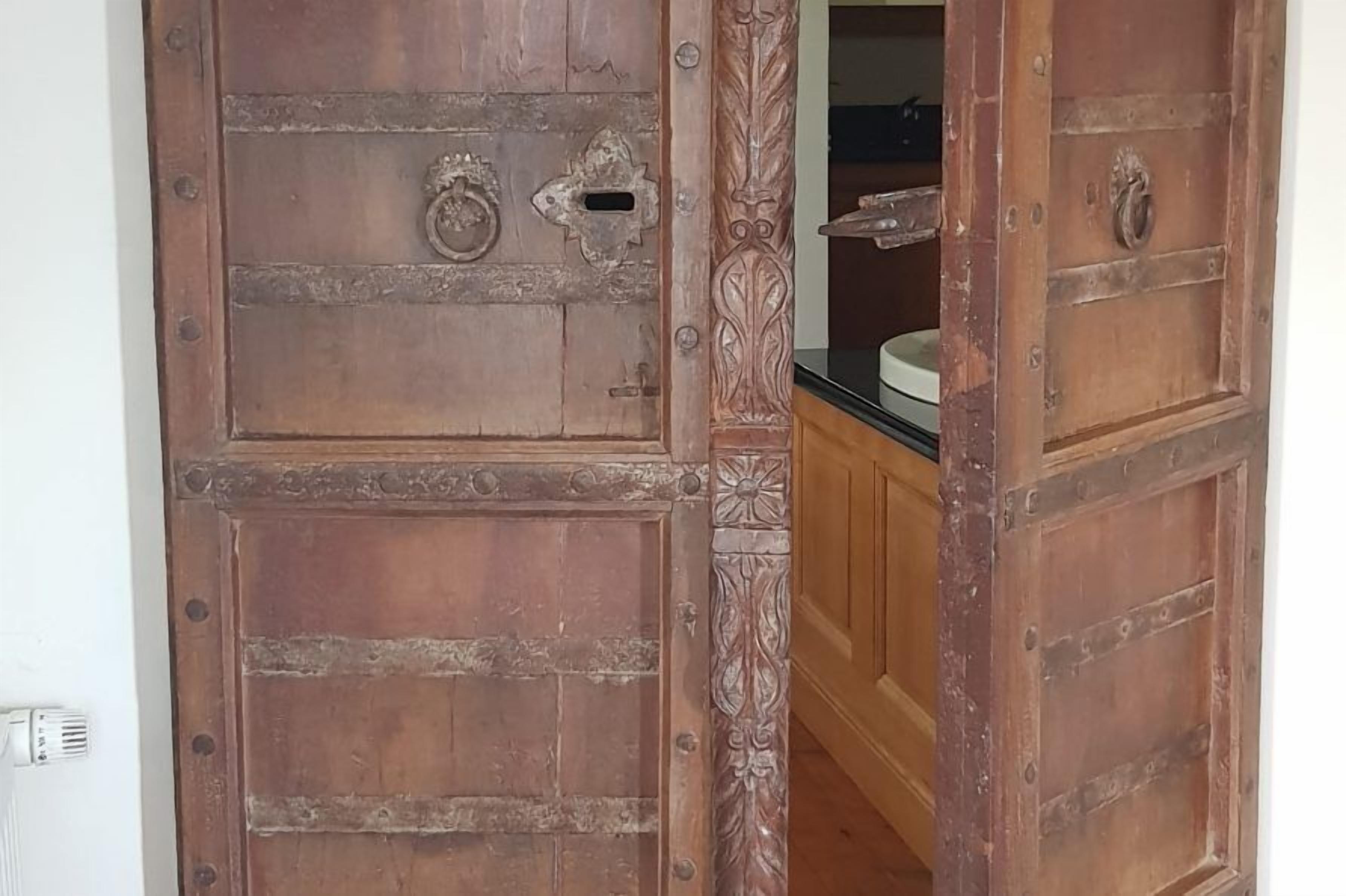 Une porte en bois au style rustique, agrémentée de poignées en métal décoratives et d’une petite fenêtre.
