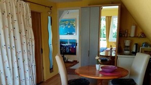 A cozy room with a bed, a dining table, and a view of a scenic landscape through the window.