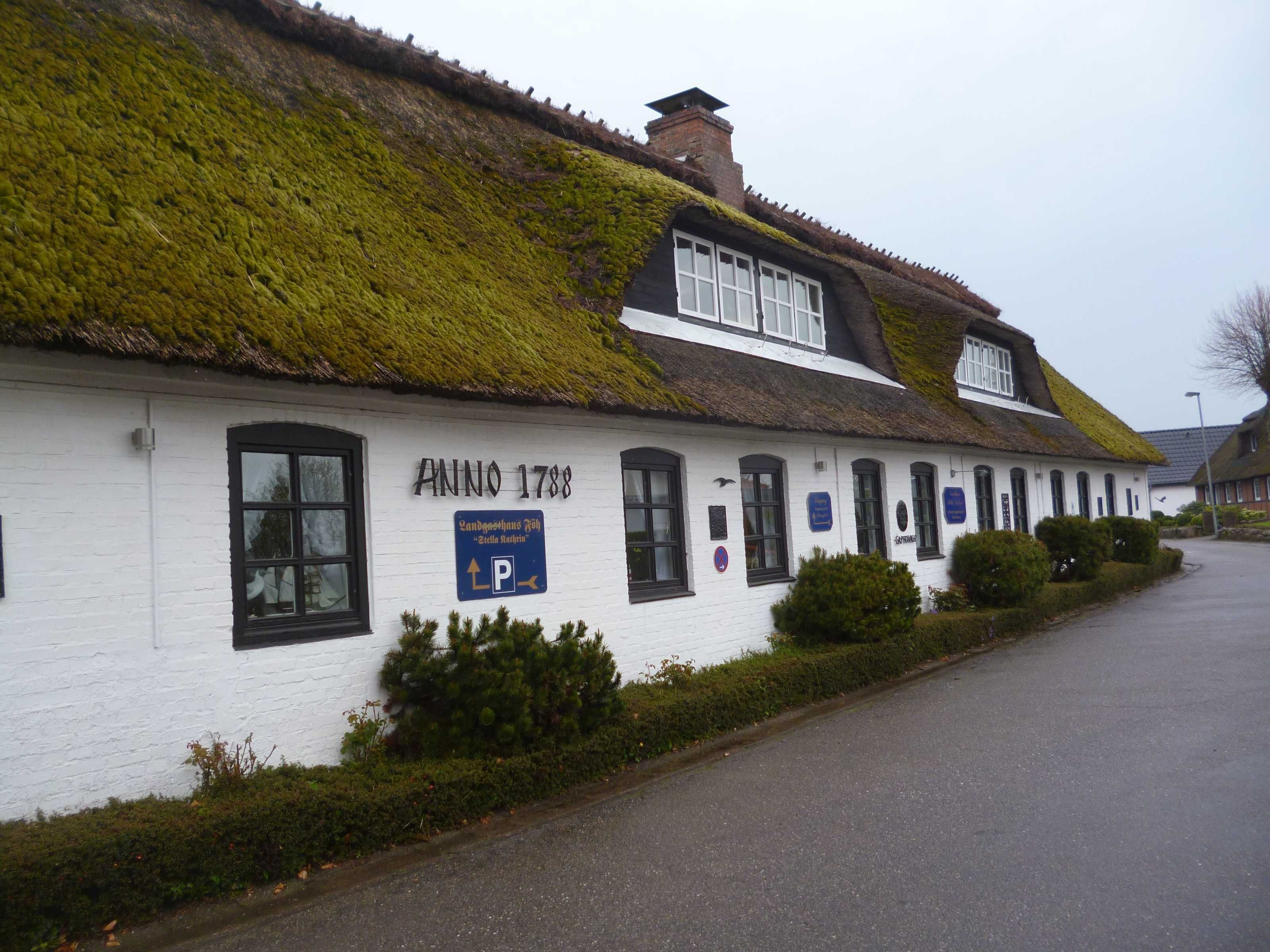 A traditional building with a white exterior, a thatched roof, and a sign reading "Anno 1788".