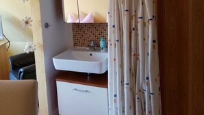 A bathroom with a white sink, a mirror above it, and a wooden door.