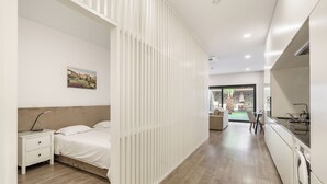 Moderni hotellihuone, jossa on sänky, yöpöytä ja näkymä ulkoalueelle.