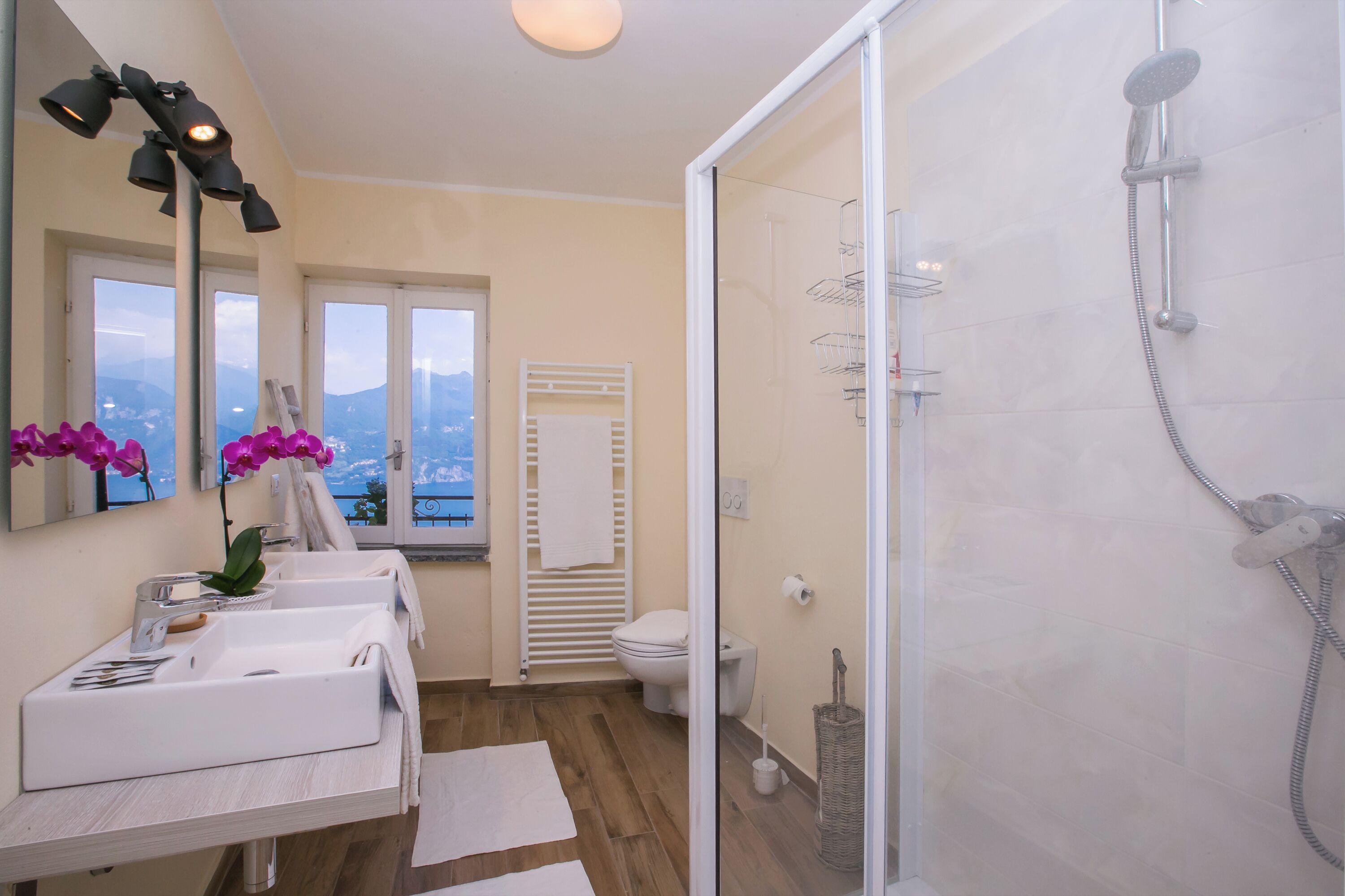Ein Badezimmer mit zwei Waschbecken, einer Dusche, einem Fenster mit Aussicht und einem Handtuchhalter.