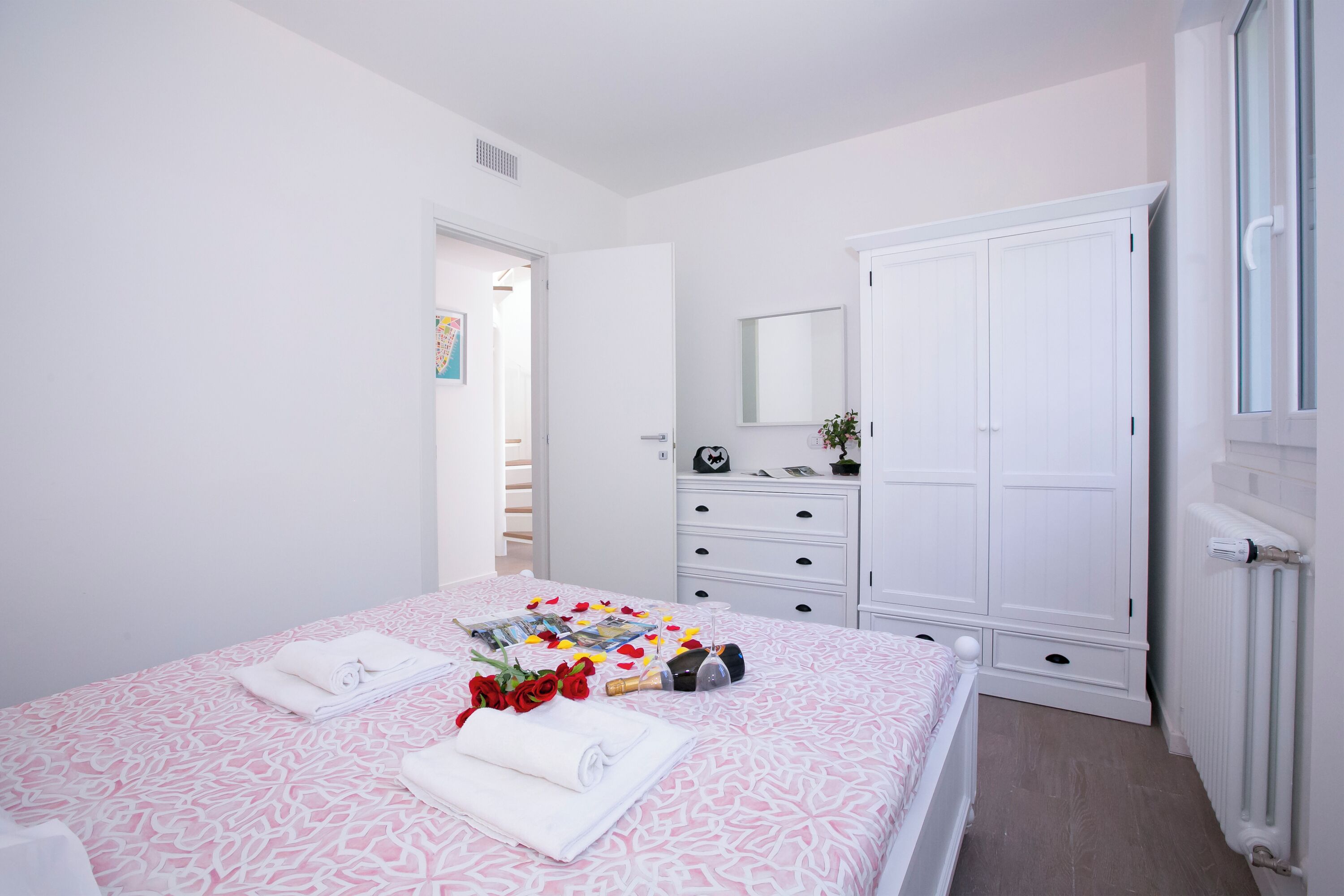 A bedroom with a bed, a wardrobe, a dresser, and a mirror.