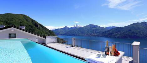 A swimming pool with a view of mountains and a lake.