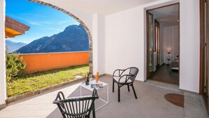 Ein Balkon mit Blick auf Berge, ein Tisch mit Stühlen und ein Durchgang zu einem Schlafzimmer.