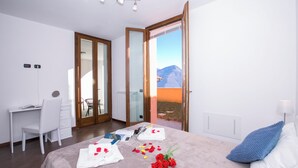 Ein Schlafzimmer mit Bett, Schreibtisch, Stuhl und Bergblick durch eine Glasdoor.