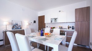 Eine moderne Küche mit weißen Schränken, einem Esstisch für vier Personen und einem Gemälde an der Wand.