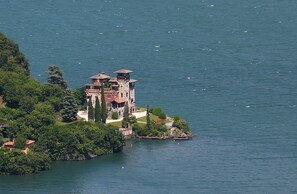 A historic building with a tower, surrounded by water and greenery.