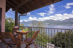 A balcony with a table and chairs, overlooking a lake and mountains.