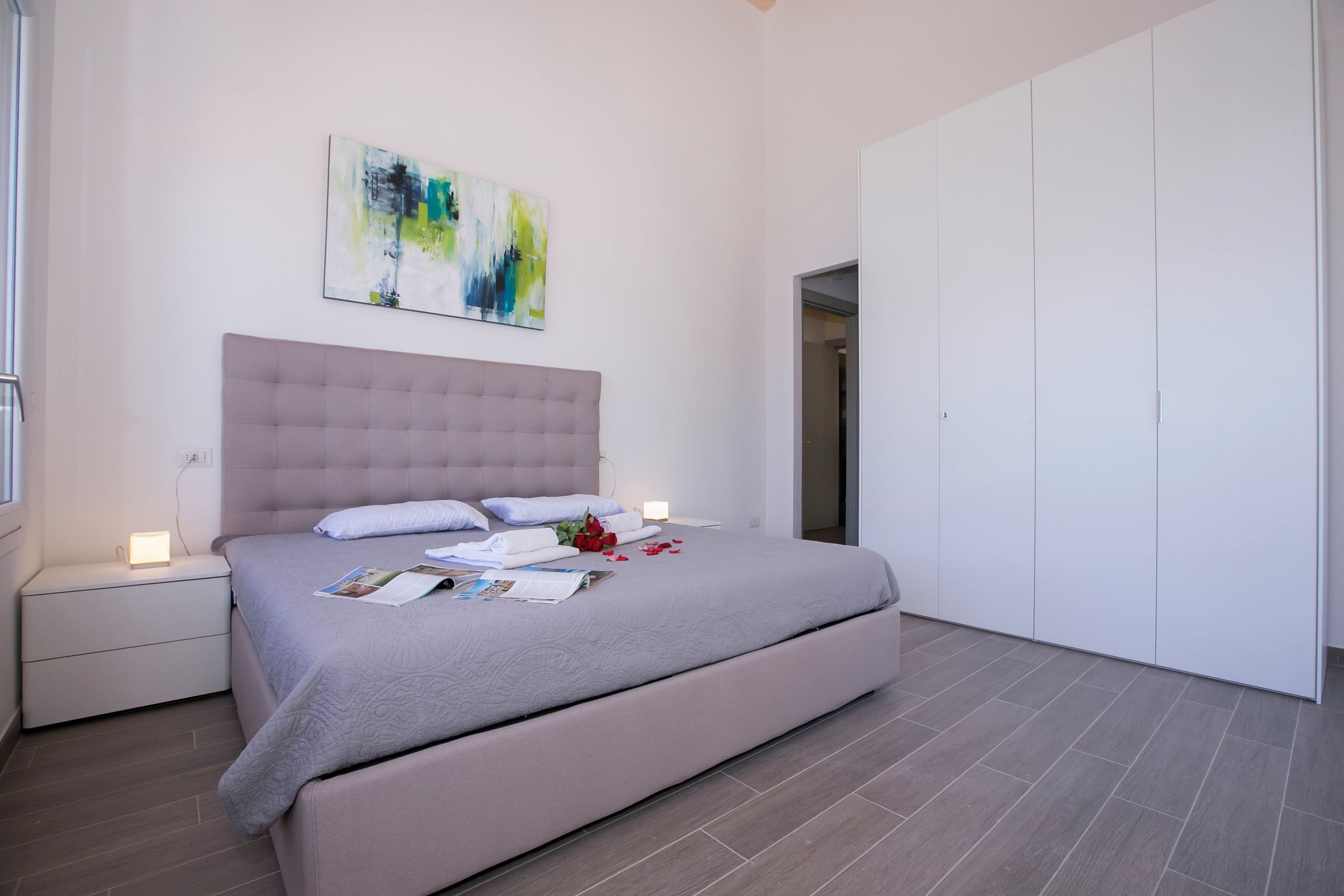 Une chambre à coucher moderne avec un grand lit, une table de chevet, une commode et une armoire.