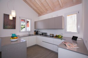A modern kitchen with white cabinets, a granite countertop, and a wooden ceiling. - Paradiso di Menaggio Penthouse (Menaggio)