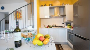 A modern kitchen with white cabinets, a stainless steel refrigerator, and a fruit bowl on the counter. - Blevio Panoramica (Blevio)