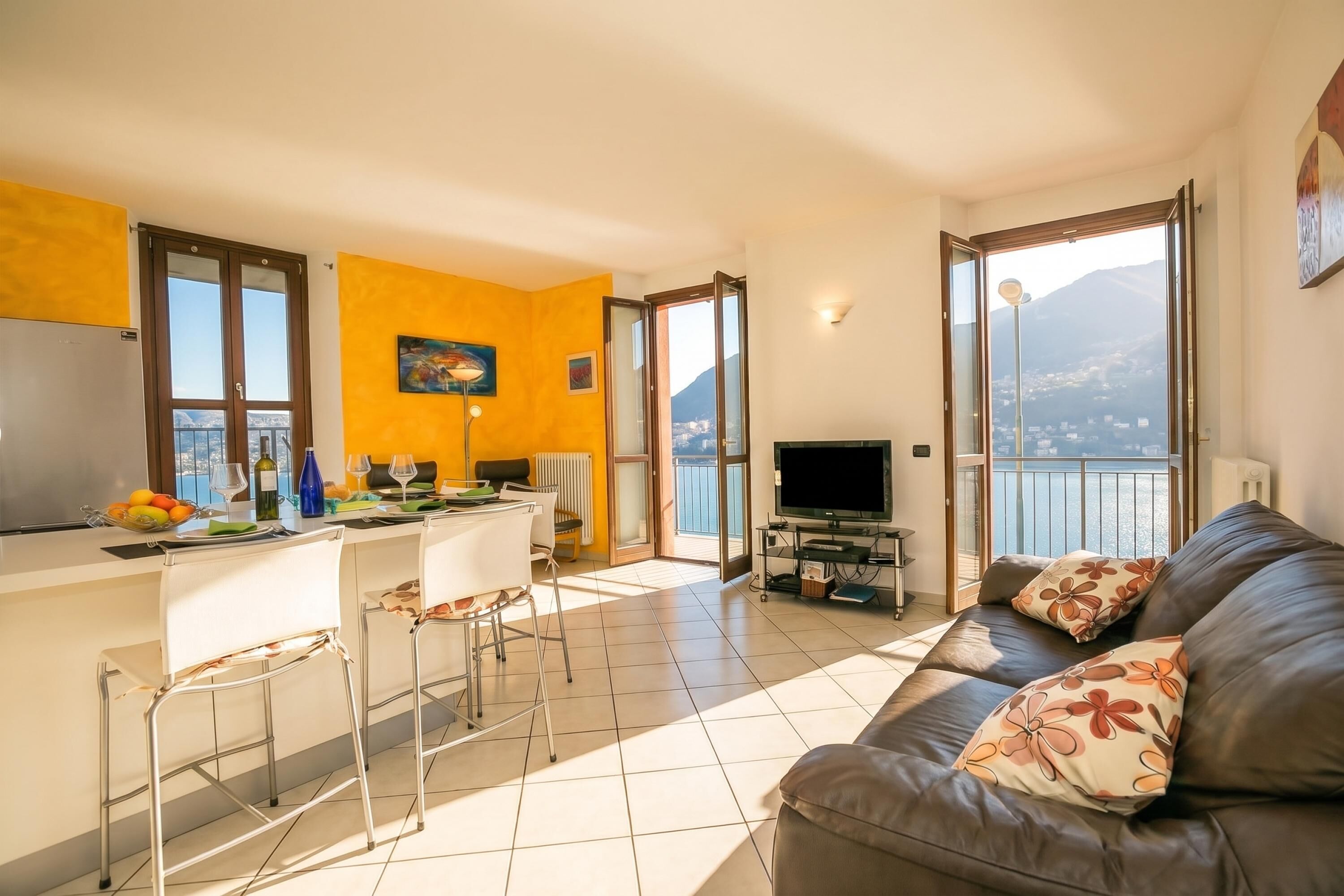 A modern living space with a kitchen, dining area, and a sofa with a view.