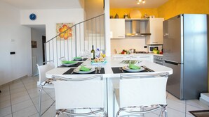 A modern kitchen with a dining area, stainless steel appliances, and a staircase leading to an upper level. - Blevio Panoramica (Blevio)