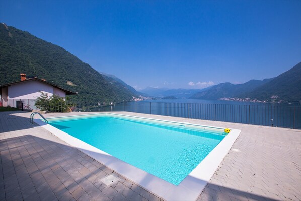 A rectangular swimming pool with a clear blue water surface, surrounded by a paved deck.
