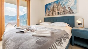 Hotelkamer met een groot bed, uitzicht op een kathedraal door een schuifdeur en een nachtkastje met een lamp.