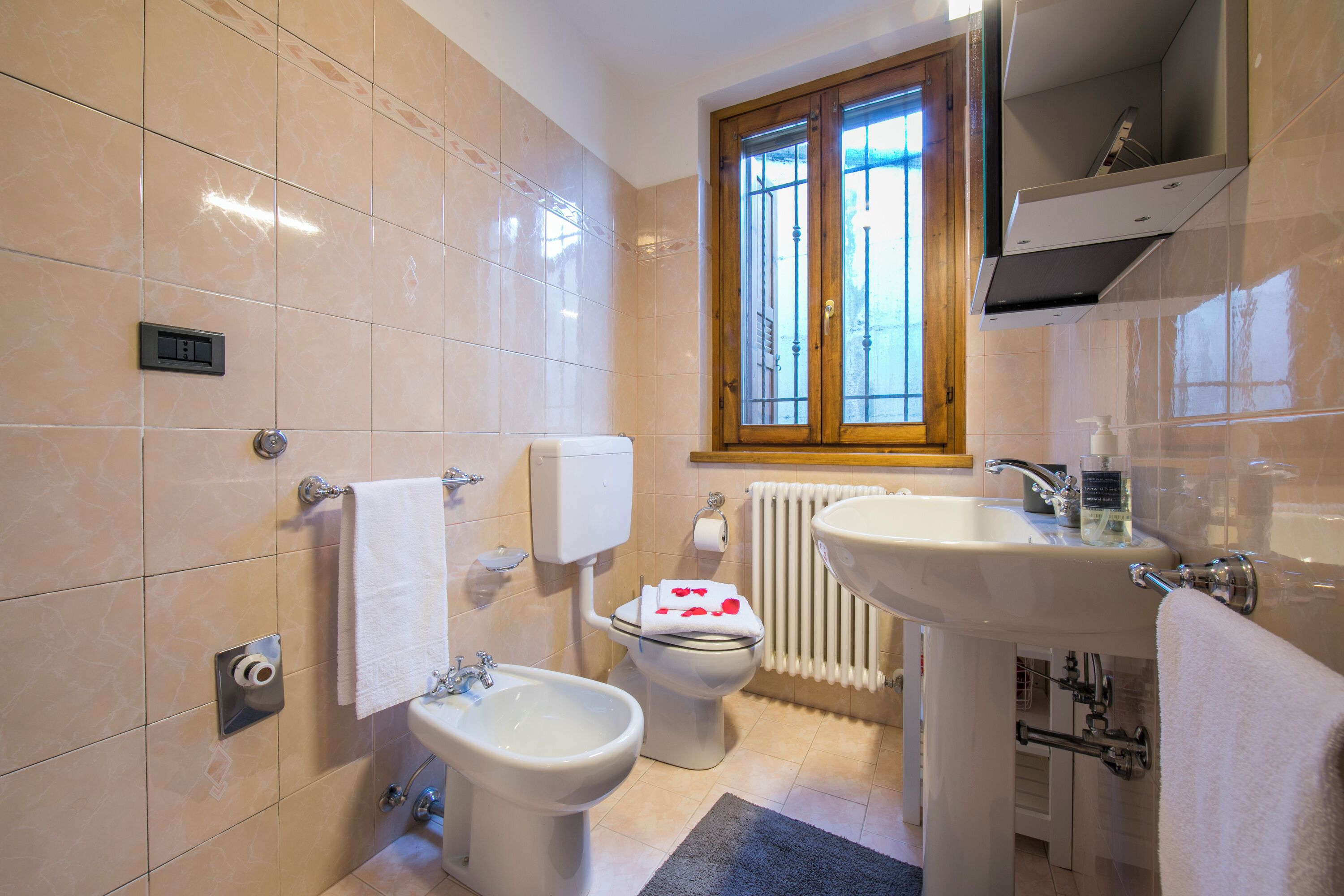 Een badkamer met een bidet, toilet, wastafel en een raam met uitzicht.