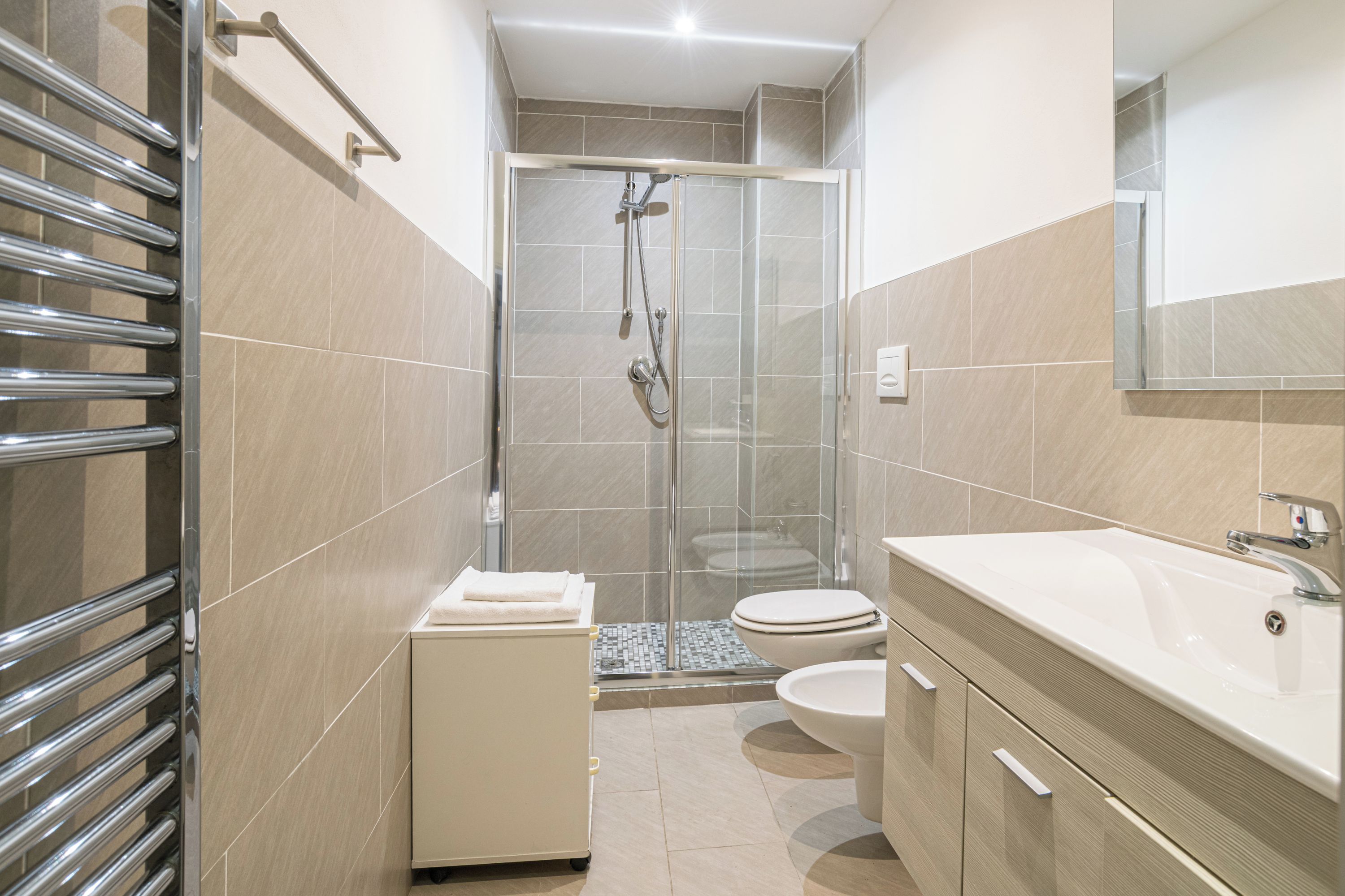A modern bathroom with a glass-enclosed shower, a white sink, and a toilet.