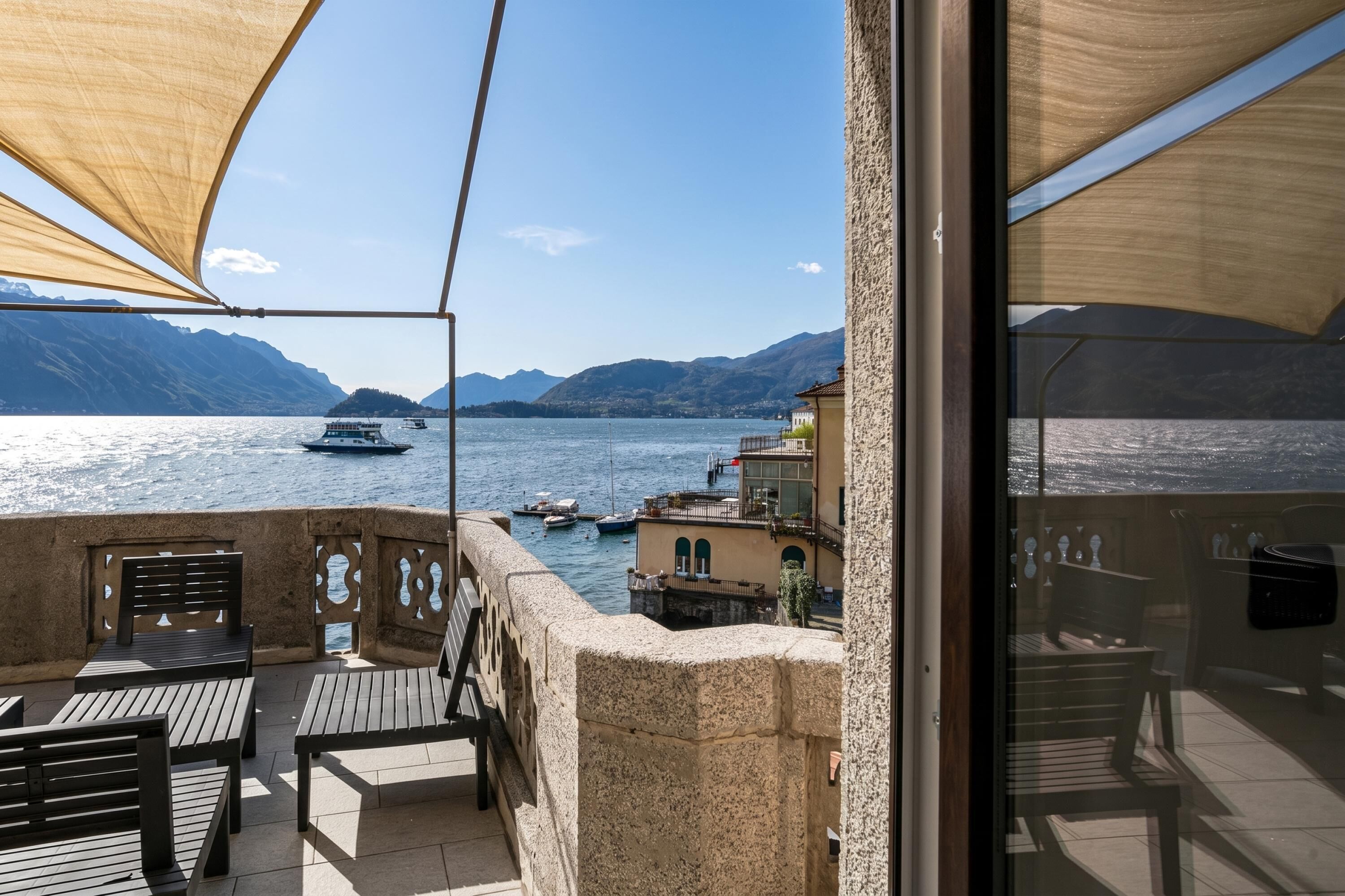 A balcony with a view of a lake, boats, and mountains.