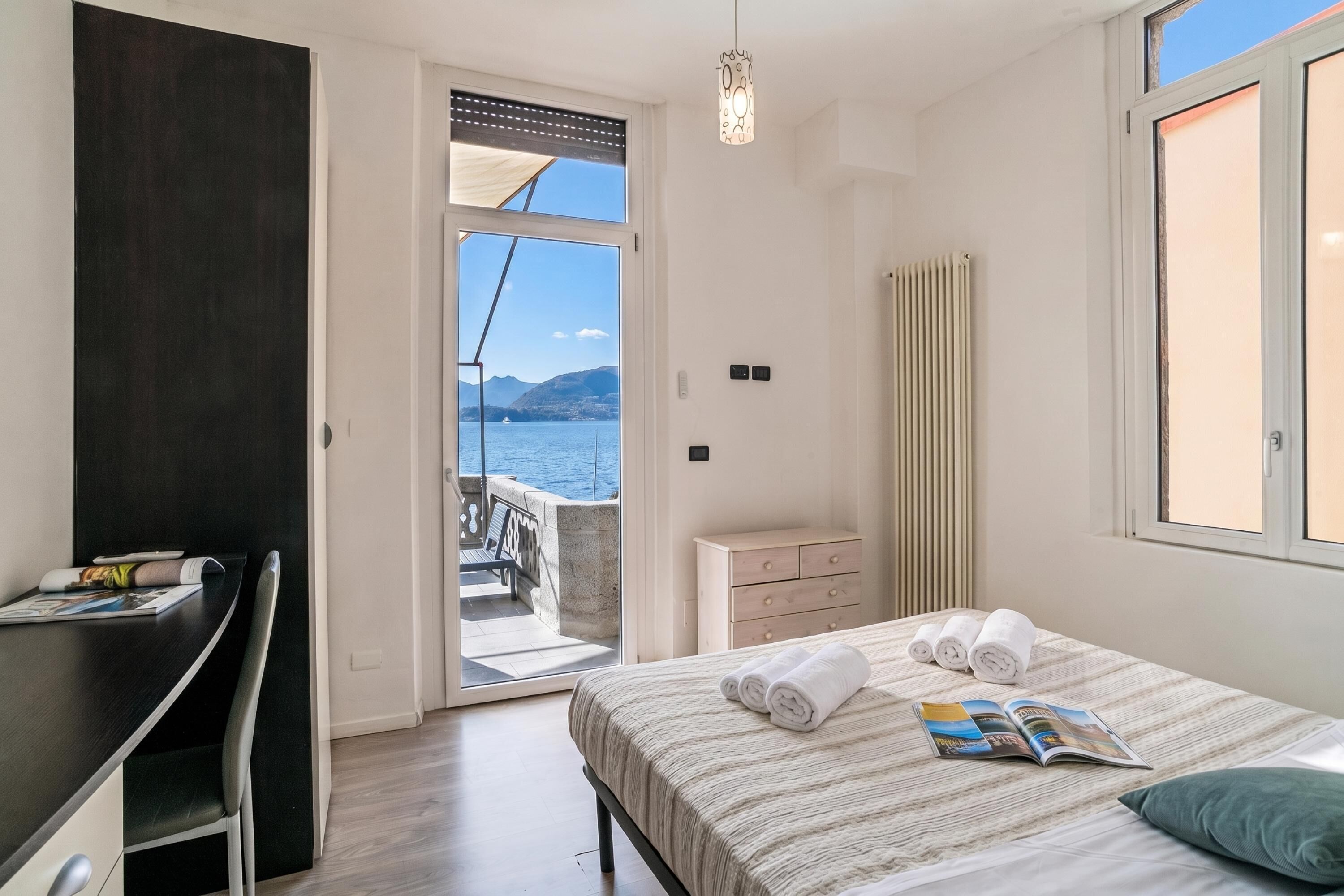 Un dormitorio con cama, escritorio, cómoda y vista al mar.