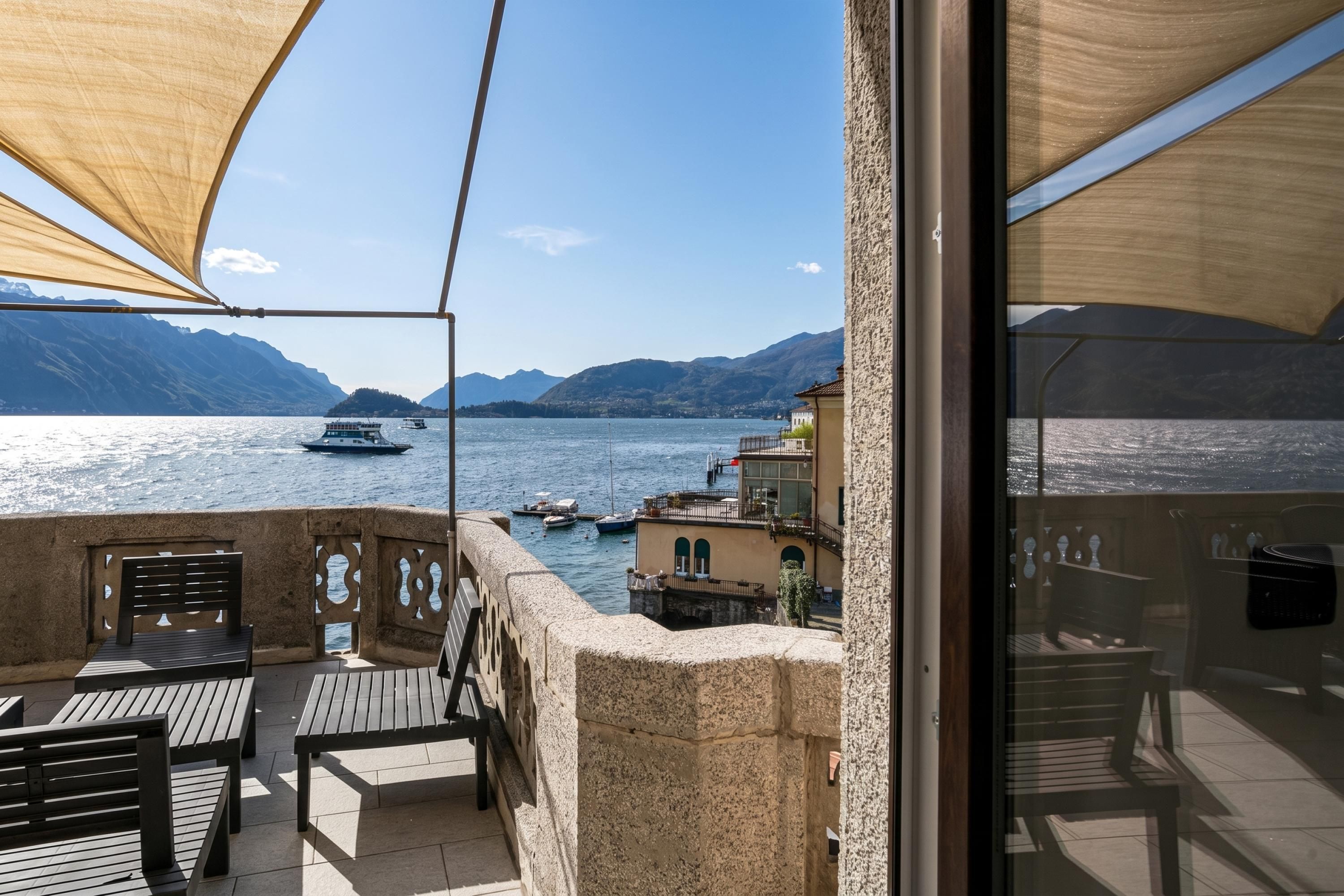 A balcony with a view of a lake, boats, and mountains.