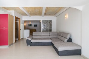 A modern living room with a sectional sofa, a red cabinet, and a kitchen area in the background. - Menaggio Tosca 2 (Menaggio)