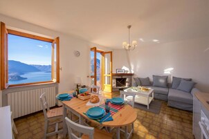 A dining area with a view of mountains, a sofa, and a fireplace.