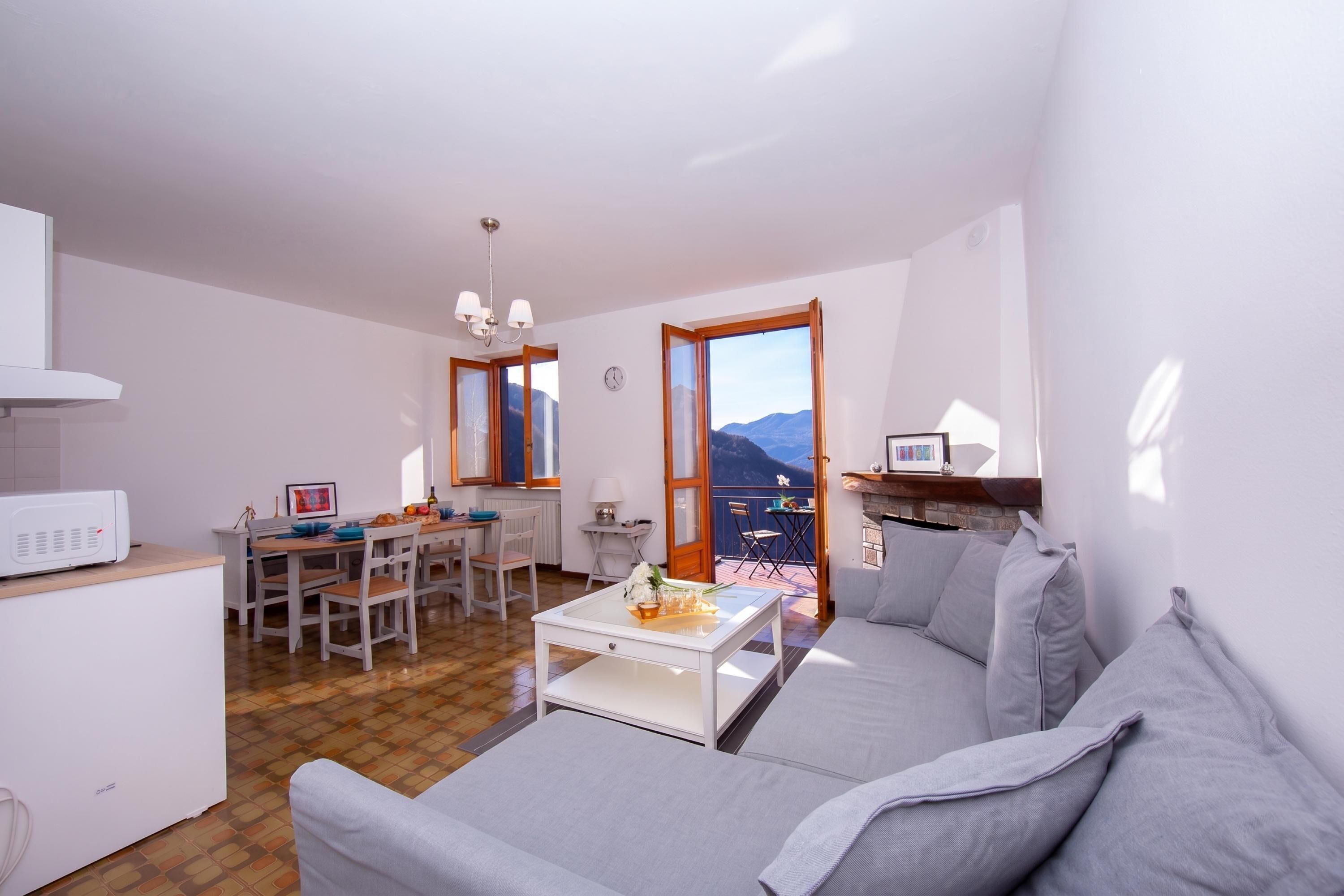 A compact living space with a dining area, a sofa, a coffee table, and a view of the mountains.
