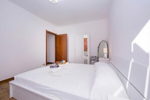 Una habitación de hotel con una cama, un armario, un espejo y una mesita de noche.