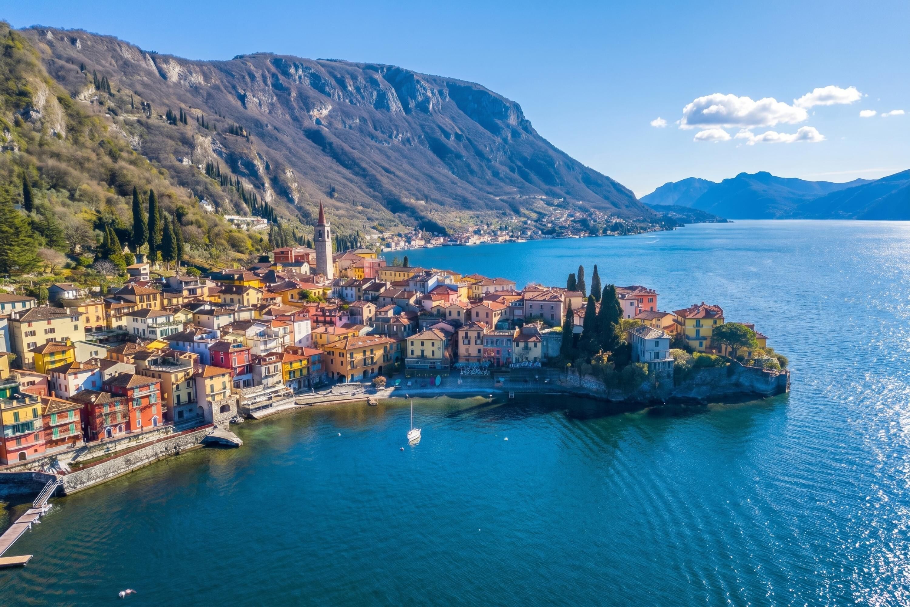 A coastal town with colorful buildings, a prominent church, and a mountain backdrop.