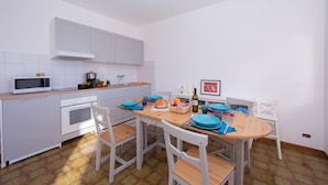 Une cuisine avec des meubles blancs, un four à micro-ondes, une cuisinière et une table à manger avec des chaises.