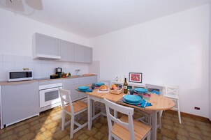 A kitchen with white cabinets, a microwave, a stove, and a dining table with chairs.