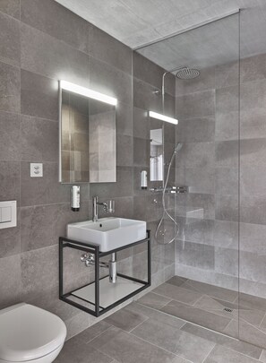 A modern bathroom with a glass-enclosed shower, a white sink, and a large mirror. - BoHo by Maier - kontaktloser Check-In (Buchs)