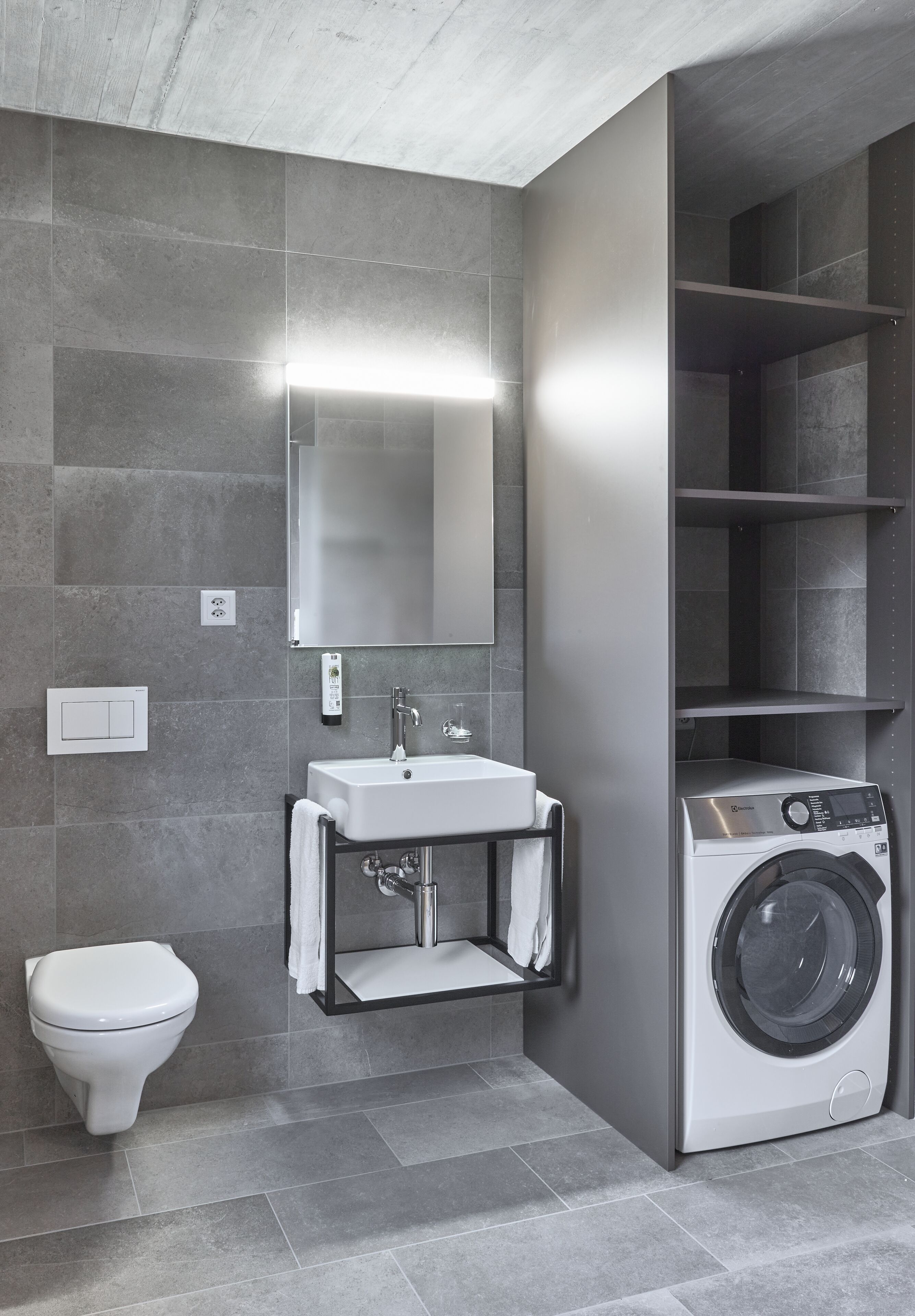 Ein modernes Badezimmer mit Waschmaschine, Waschbecken und Toilette.