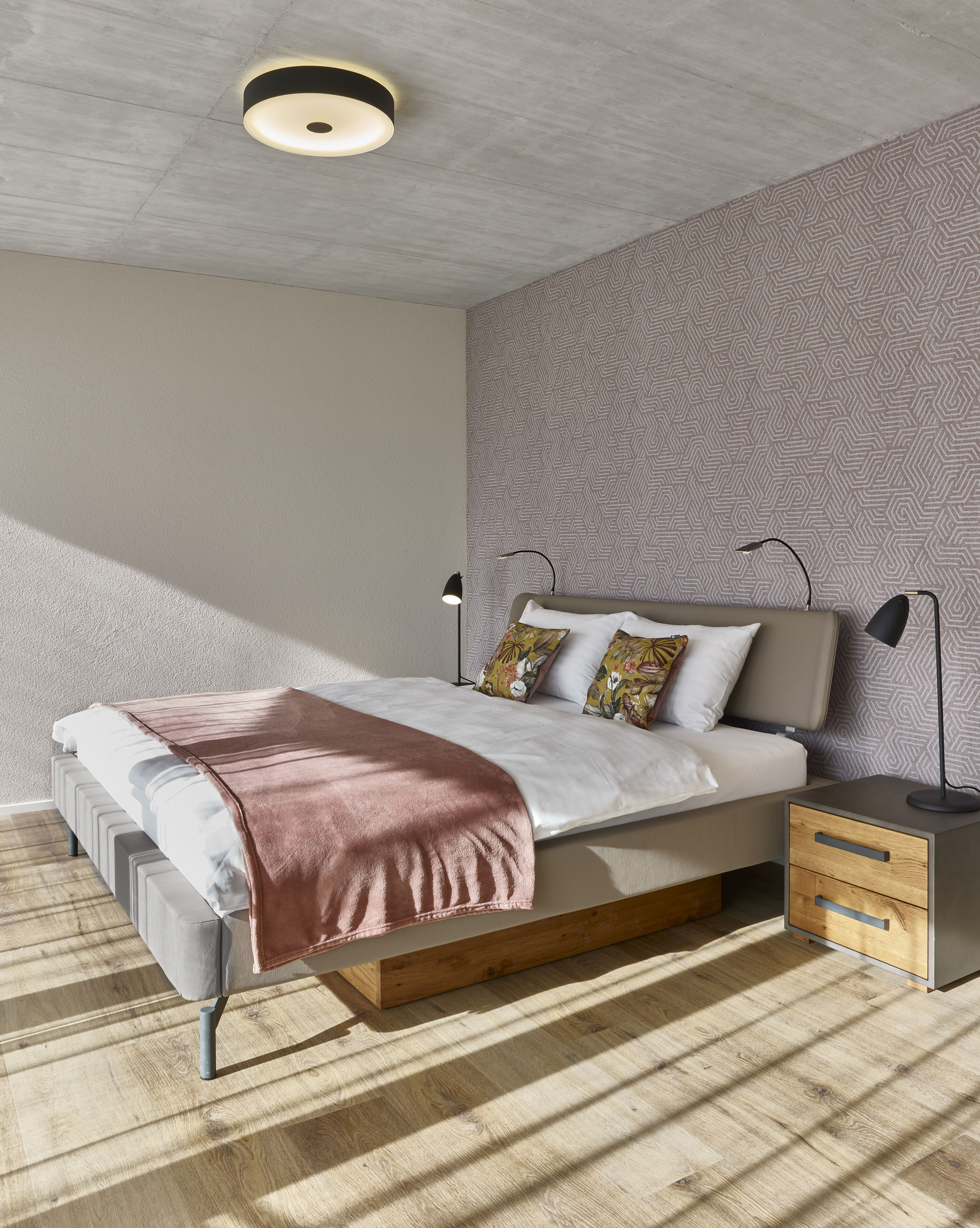 Un dormitorio moderno con cama, mesitas de noche y una pared estampada.