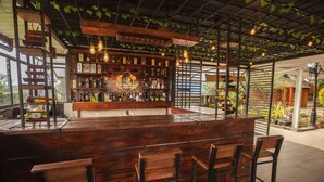 A bar area with wooden furniture, a brick wall with shelves of bottles, and hanging lights. - Hotel La Posada del Rancho (Popayán)