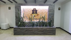 A reception area with a stone wall and a large sign featuring a logo and text. - Hotel La Posada del Rancho (Popayán)