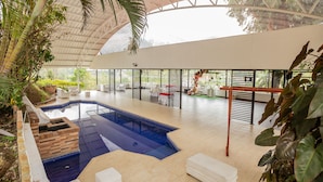 An indoor swimming pool with a brick structure, surrounded by white furniture and plants. - Hotel La Posada del Rancho (Popayán)