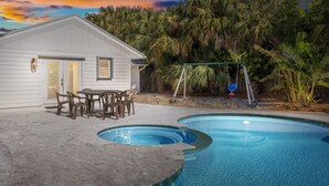 Una casa con piscina, un patio con sillas y un columpio.
