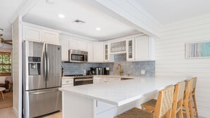 Una cocina moderna con armarios blancos, electrodomésticos de acero inoxidable y una isla grande con taburetes de bar.