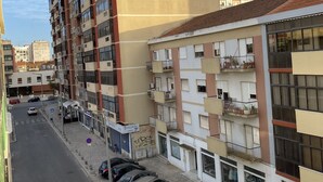 A multi-story residential building with balconies, a parking area with several cars, and a clear sky. - Barreiro Central Apartment  (Barreiro)