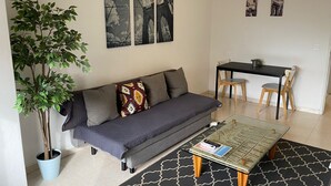 A living room with a sofa, a coffee table, a dining table with chairs, and a potted plant. - Barreiro Central Apartment  (Barreiro)